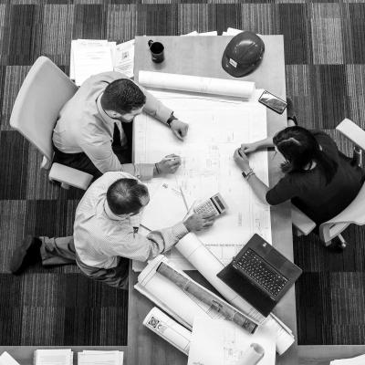 Business people meeting around a technical drawing on a table